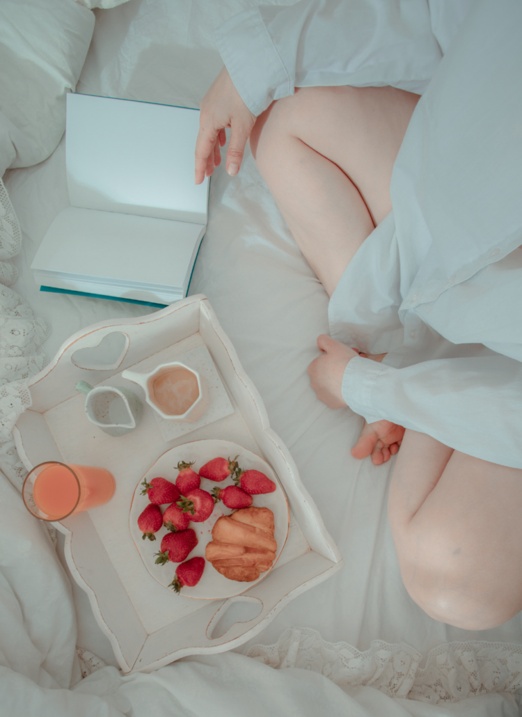 girl sitting on bed with breakfast and notebook