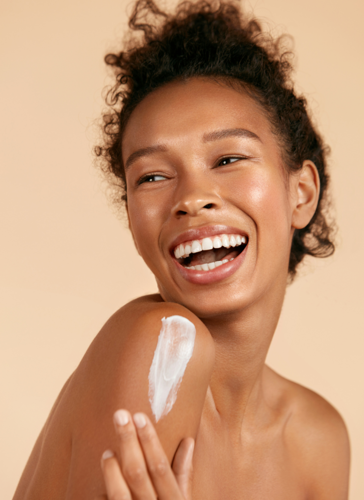 girl smiling and applying a moisturizer