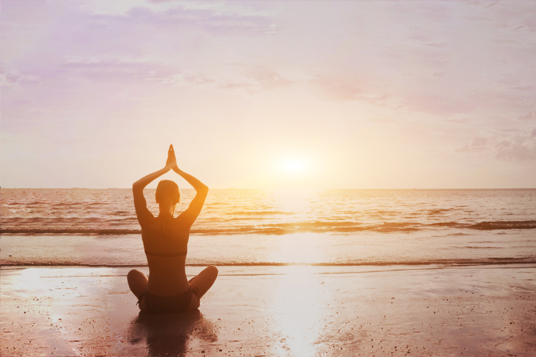 self care: woman doing yoga on beach sunset