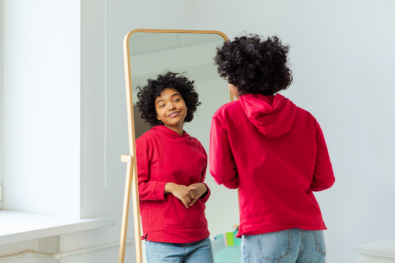 self care: girl smiling in mirror