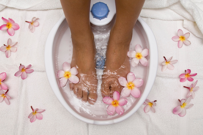 girl sitting her feet in a foot spa with flowers