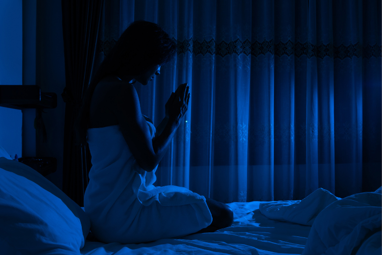 woman praying in bed at nighttime
