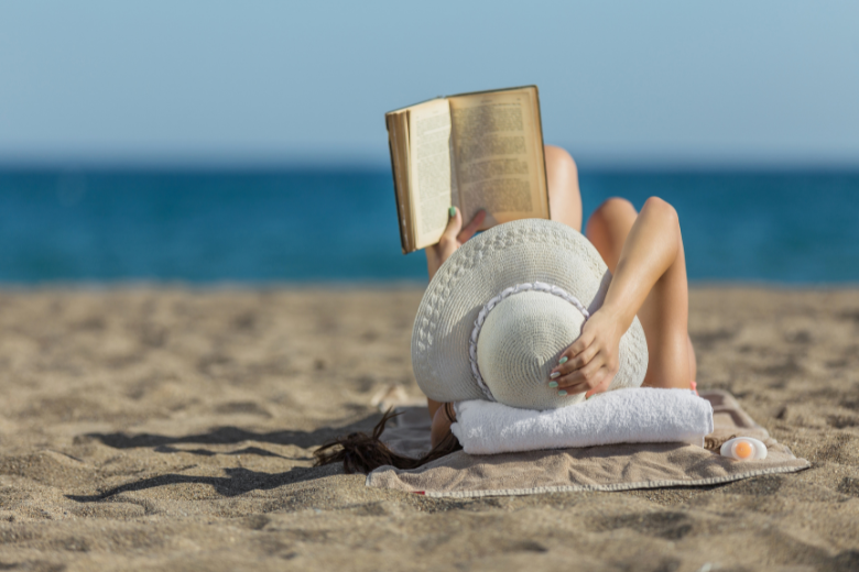 girl-reading-on-beach-wearing-big-white-hat
