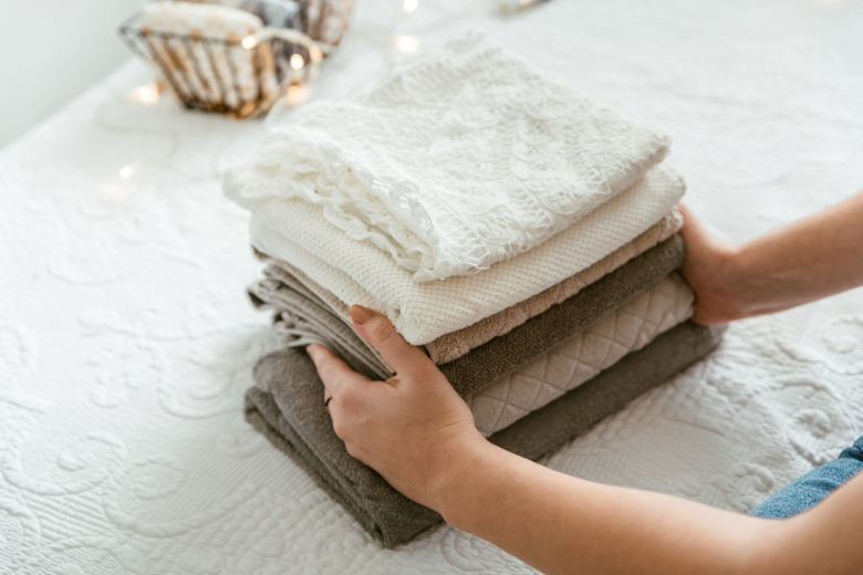 woman placing stack of towels on bed