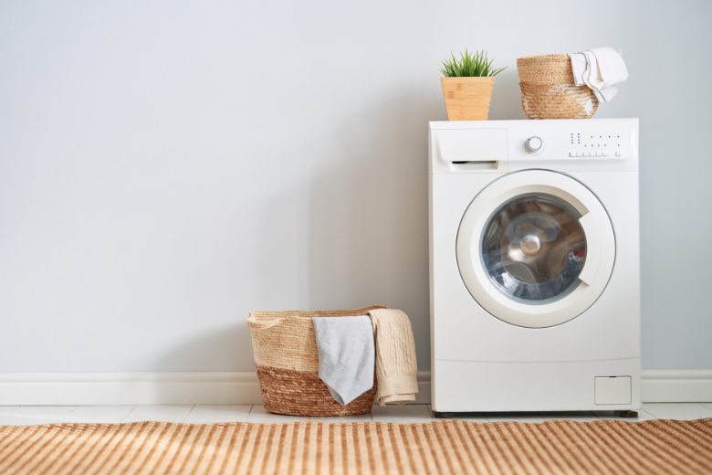 white washing machine with wooden basket and plant setting atop it