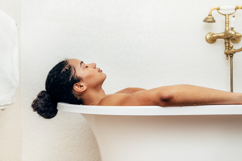 woman soaking in bath with hair in bun