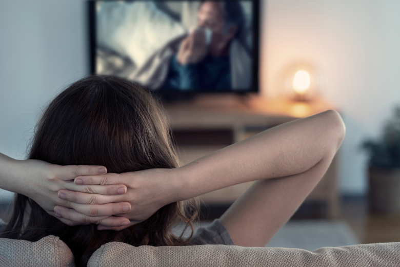 woman with hands on head watching TV