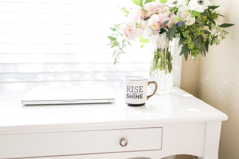 white-mug-saying-rise-and-shine-sitting-on-white-desk