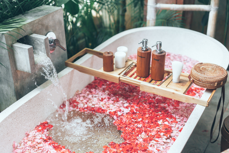 cosmetic-products-on-bath-tub-with-flower-petals-fillling-with-water